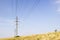 High voltage line beneath blue cloudy sky. Electrical powerlines behind wheat field against a background of clear sky in summer da