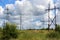 High-voltage poles stand in a flowering meadow. Power line in the countryside. Electric station supplying electricity to the city