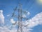 High voltage power line against blue sky with clouds. Electrical infrastructure