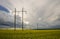 High-voltage power line in the field of blooming yellow rape flowers on the background of the sky with storm clouds