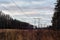 High voltage power lines above frost field and cloudy morning sky. Landscape with power pylons of a power Line in the cleared area