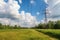 High voltage power lines on the background of green field and blue sky, Modern electrical utility lines with a blue sky, AI