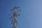 High Voltage Power Lines intersect at a large metal Utility pole in Maine against a blue sky.