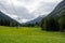 High voltage power lines and lattice cross running through remote alpine mountain valley