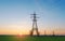 High-voltage power lines passing through a green field, on the background of a beautiful sky