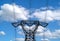 High voltage pylons against a blue sky with white clouds.