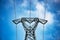 High voltage pylons against a blue sky with white clouds.