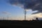 High voltage pylons. Sunset behind storm clouds. Electrical distribution network.