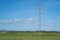 High voltage tower and cable line in the countryside under a blue sky