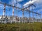 High-voltage towers on a background of blue sky and green grass. Red and white pipe with steam from a power plant