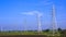 High voltage towers with cable lines in countryside with blue sky