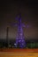 High voltage towers lightened with violet light in evening