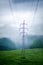 High voltage towers in a middle of forests and meadow. Electricity pylon with dark atmosphere in a nature. Rainy day. Power transm