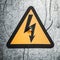 High voltage triangle sign on gray metal wall