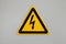High voltage triangle warning sign mounted on gray