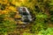 High waterfall in the colorful foliage of autumn forest at Oirase Stream Walking Trail