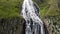 High waterfall with fast water streams flows among cliffs