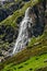 High waterfall and green hill in the mountains