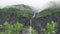 High waterfalls in misty mountains in Norway with greenery in the foreground