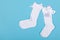 High white children`s socks with big bows for festive clothes on a blue background top view