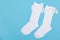 High white children`s socks with big bows for festive clothes on a blue background top view