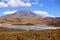 Highland mountains in the Bolivian Andes. Calm waters lake and an off road vehicle in the desert.