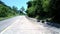 Highland road past stone wall with green dense forest