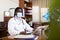 Highly qualified african american doctor in a protective mask types on a computer in the resident's office