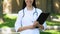 Highly qualified doctor with folder and stethoscope smiling standing outdoor