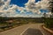 Highway Bend against Hilly Countryland Blue Cloudy Sky