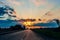 Highway with cars traveling on the sunset. Horizon line with the sun and storm clouds. Journeys