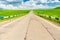 Highway, green field and beautiful clouds on a sunny day