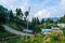 A highway in a mountain and greenery by the side. Many houses by the sides