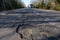 Highway with potholes. Poor quality pavement in the primary stage of its destruction. On the road car