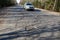 Highway with potholes. Poor quality pavement in the primary stage of its destruction. On the road car