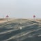 Highway road among desert during sand storm with road signs with camel warning