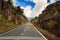 Highway between Rocky Hills Distant Bus Blue Sky