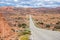 Highway running through dry and arid scenery of Glen Canyon National Recreation Area