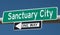 Highway sign with SANCTUARY CITY and ONE WAY