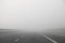 highway with very dense dangerous fog without cars in winter