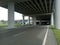 The highway is wide and quiet, with a flyover building above it