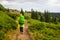 Hike backpacker lifestyle girl walking on trek trail in mountains outdoors with yellow raincoat and green raincover.
