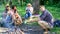 Hike picnic ideas. Hikers sit near campfire relaxing while wait roasting food. Hikers organized quick picnic to eat and