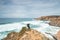 Hiker and adventurer stand on a rugged rock and cliff coastline and enjoy the view on the Atlantic Ocean in the west of Portugal