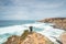 Hiker and adventurer stand on a rugged rock and cliff coastline and enjoy the view on the Atlantic Ocean in the west of Portugal