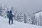 Hiker, with backpack, is climbing on the mountain range, and admires snow-capped peak. Epic adventure in the winter