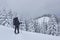 Hiker, with backpack, is climbing on the mountain range, and admires snow-capped peak. Epic adventure in the winter