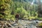 Hiker with backpack crossing mountain river. Hiking river crossing on the stones.