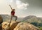 Hiker with backpack standing on top of a mountain with raised ha