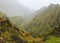 Hiker with backpack on the top of mountain edge. Rocky terrain in front of a incredible panorama view of high mountain